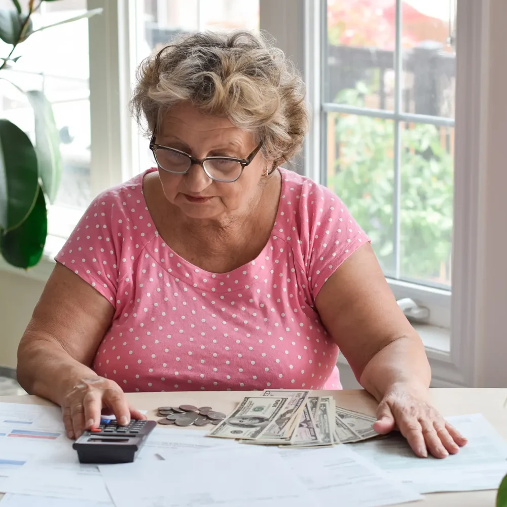 senior-woman-sitting-at-desk-using-calculator